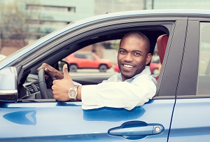 man sitting in drivers seat holding thumbs up