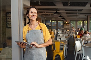 business owner standing outside cafe with a tablet