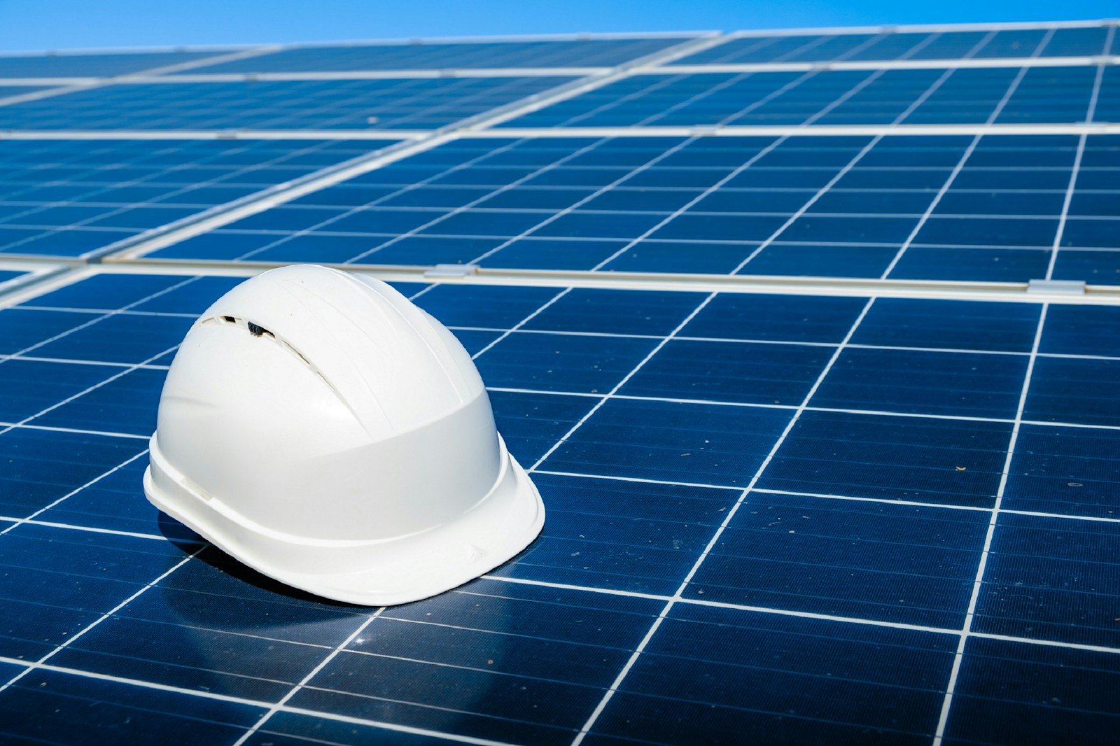 a white hard hat sitting on top of a solar panel symbolizing contractors insurance